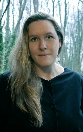 Portrait of a white woman with blond hair against a green background.