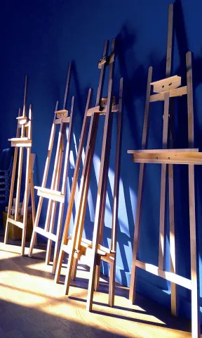 Easels lean against a deep blue wall.