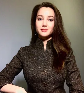 Woman with dark long hair looks friendly into the camera.