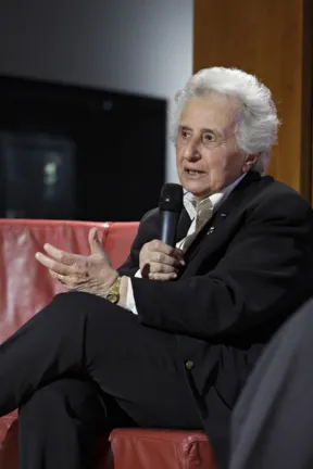 Older lady with microphone in armchair, talking