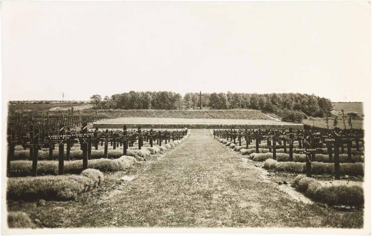 Black-and-white photograph: cross-shaped grave markers on the left and right, divided by a central path to a hill with a tall