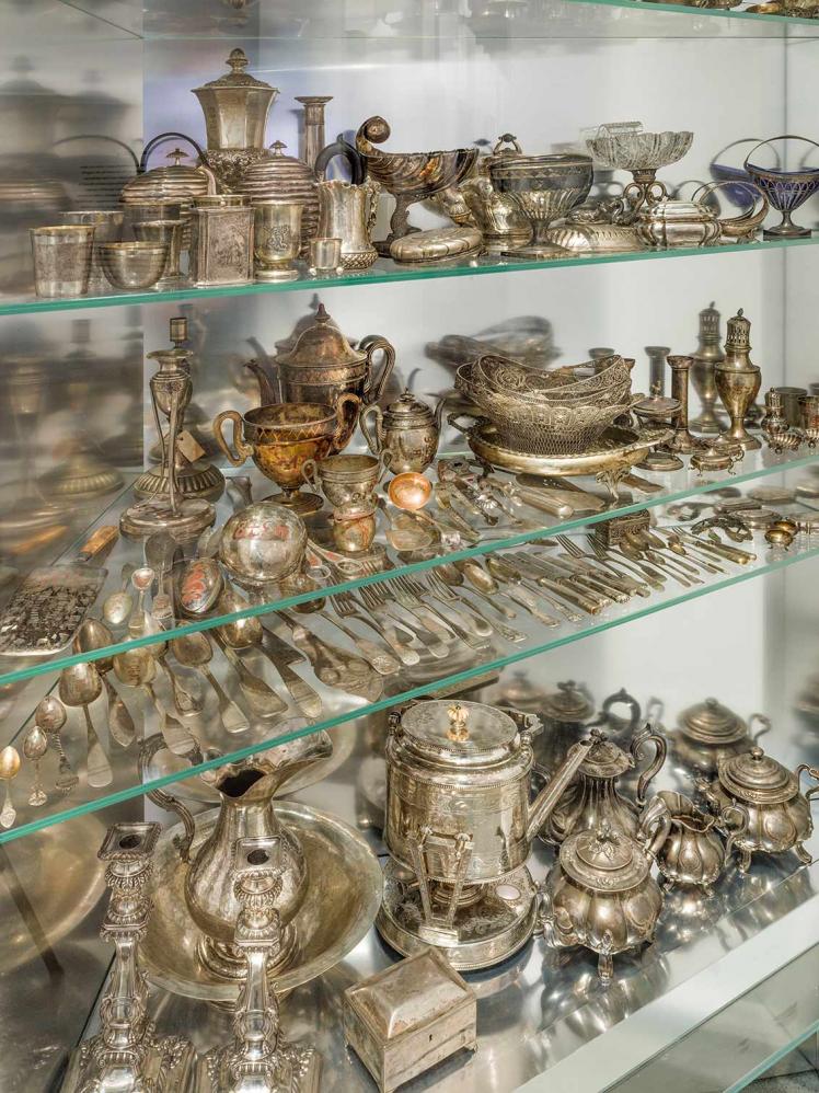 Glasvitrine voller Geschirr, Besteck und sonstiger Gegenstände aus Silber