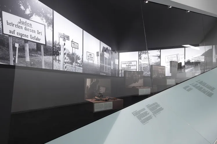 Fotografie: Blick in eine Vitrine mit Fototgrafien von antisemitischen Schildern 