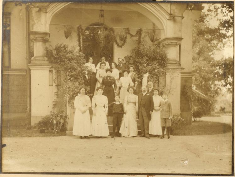 Sepia Fotografie, die die Hochzeitsgesellschaft auf einer geschmückten Veranda zeigt.