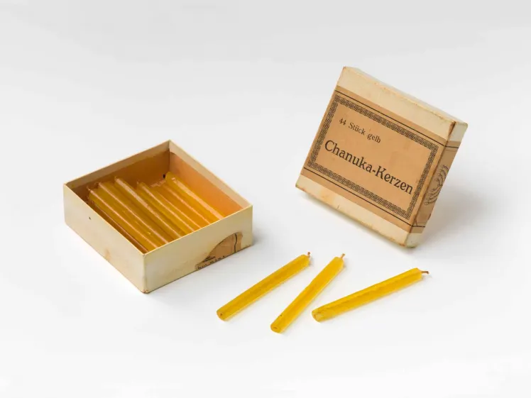 An old, opened cardboard-box with yellow candles.