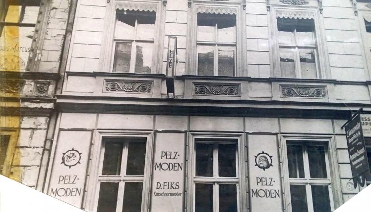 Schwarz-Weiß-Foto: Fassade eines Wohnhauses mit Werbung zwischen den Fenstern