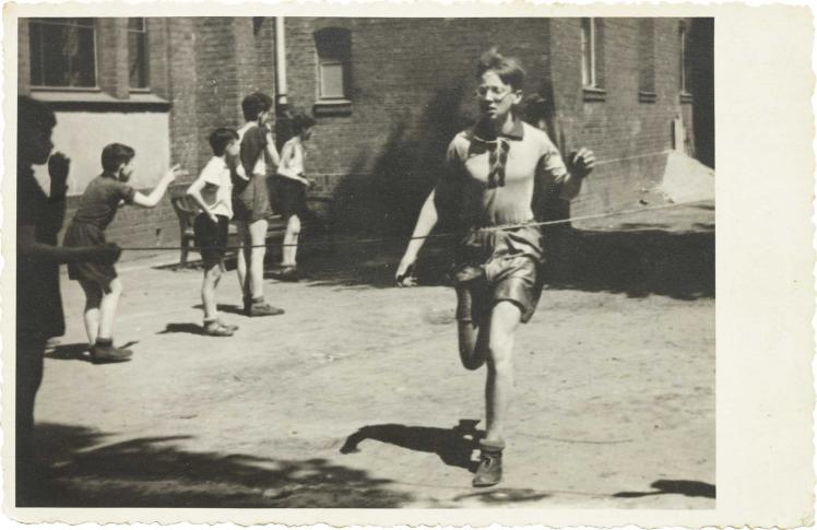 In the foreground of the picture you can see a running boy, who is about to reach the finish line, boys watching in the background (black and white photo)