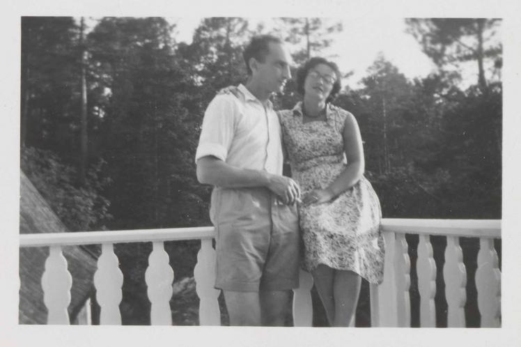 In the black-and-white photo, Leonie is sitting in a summer dress on the rail of a balcony. Walter stands next to her with his left arm around her and holding a cigarette in his right hand.