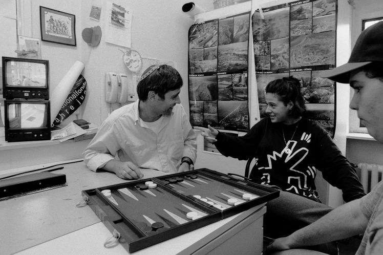 Black and white photography: a man with kippa is playing Backgammon with two kids