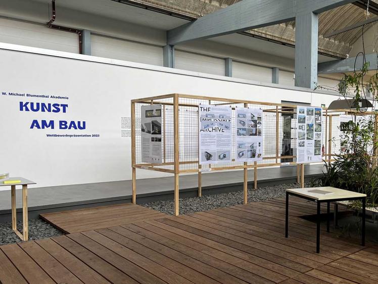 Partition walls made of wooden slats and grids in an industrial hall, to which graphic design drawings are attached.