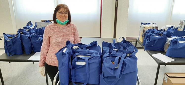 A woman with a surgical face mask pulled down standing between many packed bags