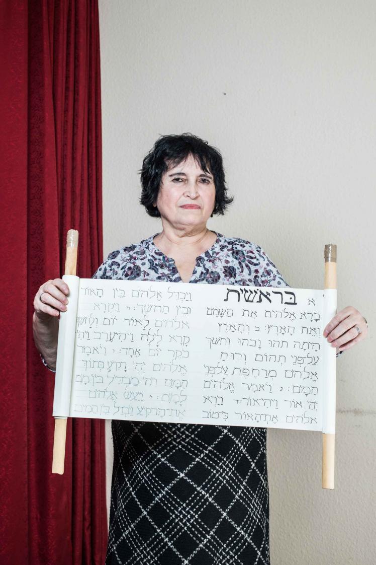 A woman holds a homemade torah scroll in her hands