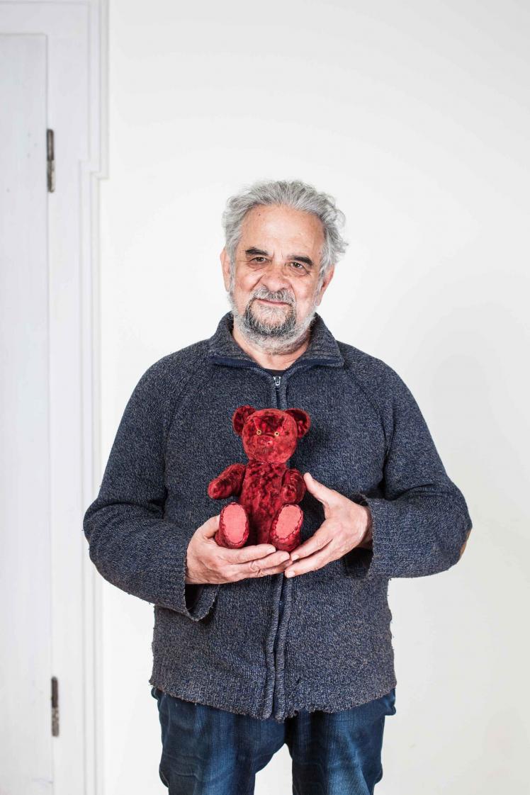 Elderly man holding a red teddy bear in his hands