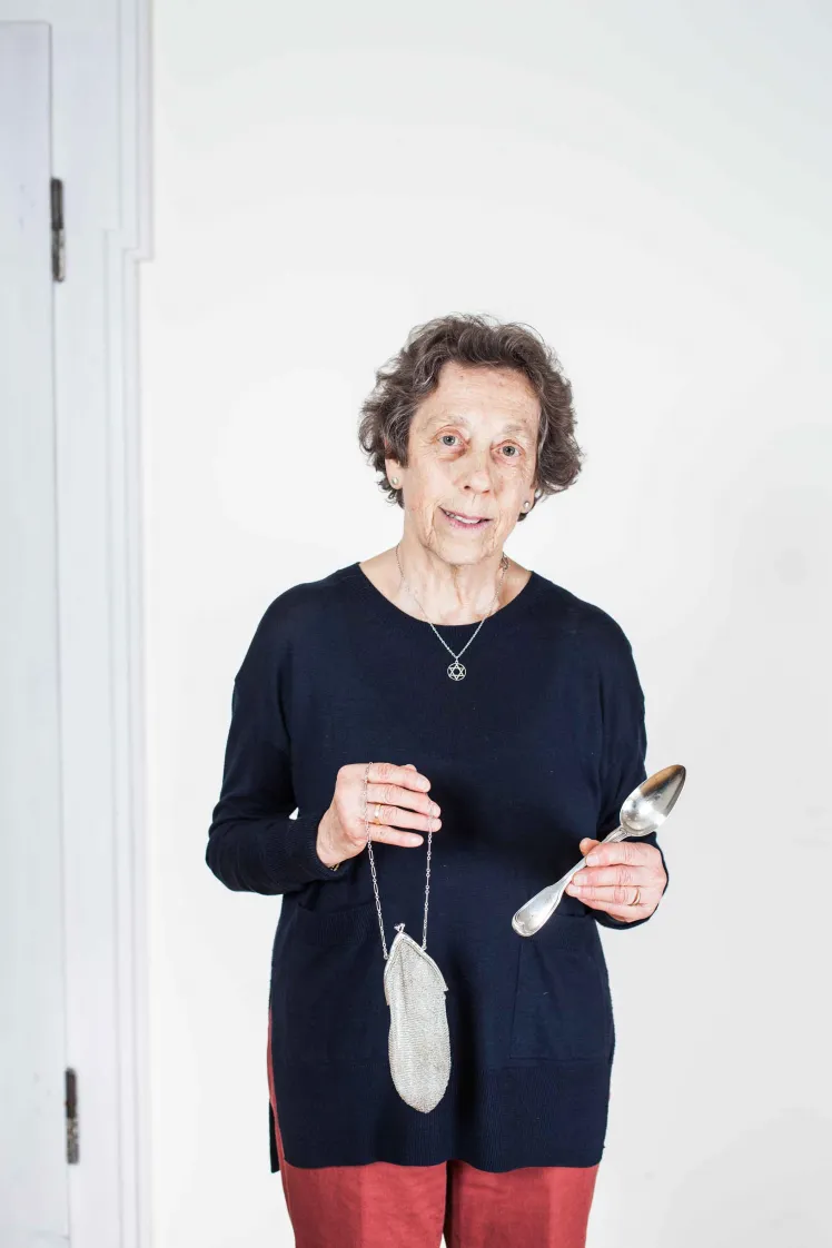 Ältere Dame hält ein silbernes Täschchen und einen silbernen Löffel in Händen