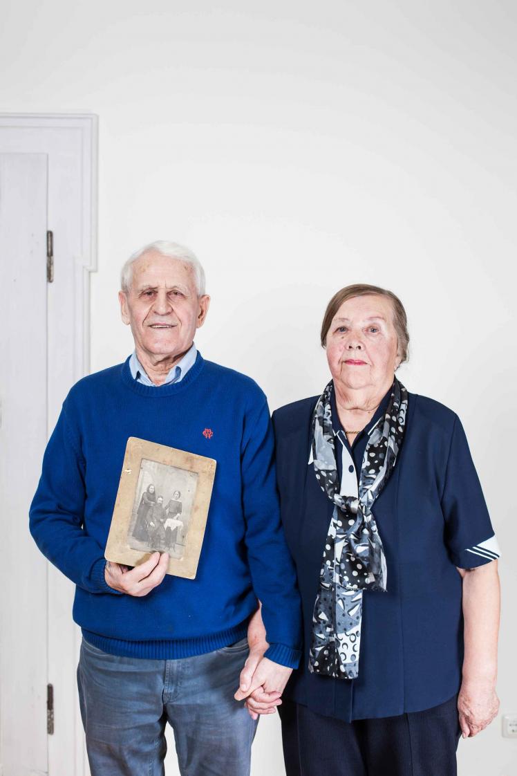 An elderly couple holding an old black and white photograph in their hands