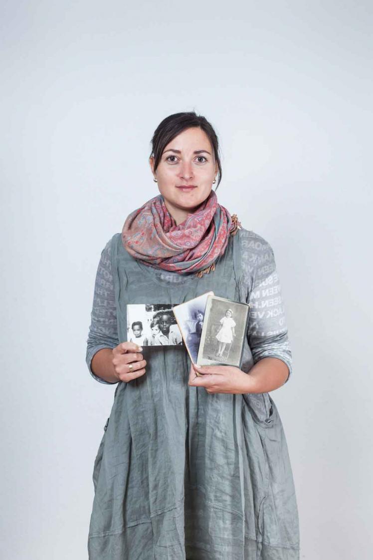 A young woman holding black and white photographs in her hand