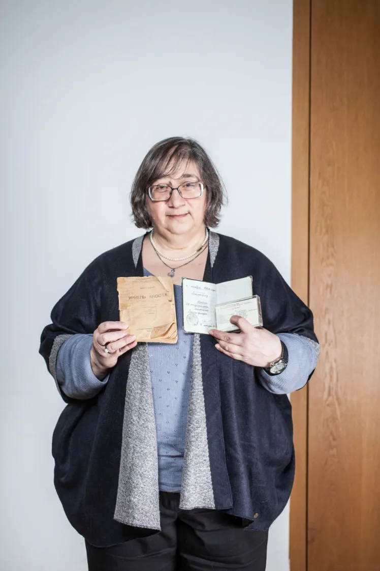 Eine Frau zeigt einen Pass und andere Dokumente. 