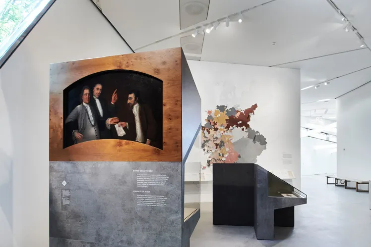 A view of one of the exhibition rooms. In front you can see a painting, in the background there is a detailed map of German territories during the Early Modern Ages.