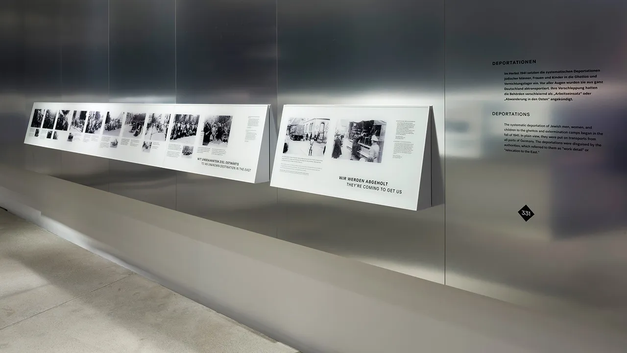 Ein Ausstellungsraum mit schwarz-weißen Bildern an einer metallenen Wand