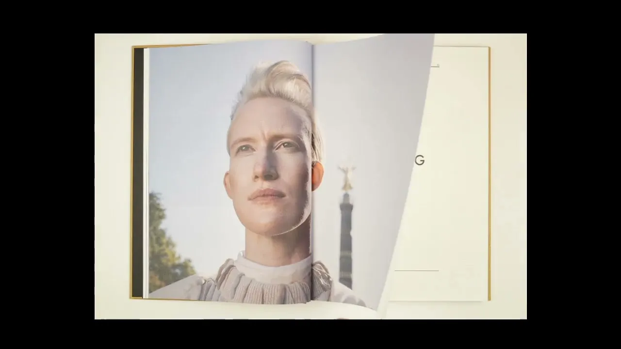 Aufgeschlagenes Buch mit einem Fotoportrait. Im Hintergrund ist die Berliner Siegessäule zu sehen.