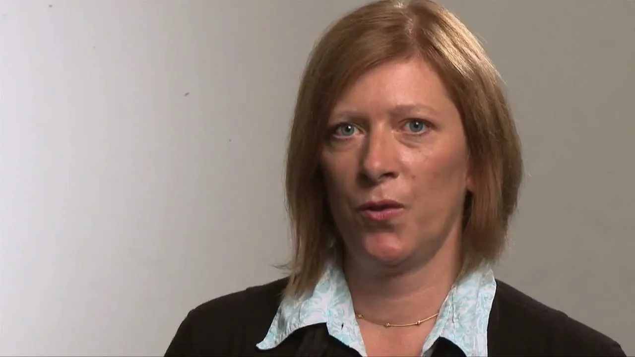 Frau mit rotblonden Haaren blickt in die Kamera uns spricht.