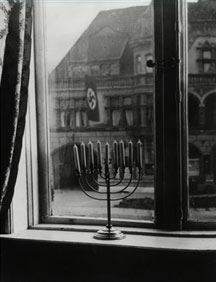 Hanukkah menorah on the window sill: View through window to a swastika flag